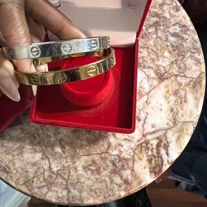 2 INSPIRED by Cartier love bracelets. 1 is gold plated. 1 is stainless steel